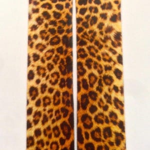 May include: Two socks with a leopard print pattern. The socks are primarily tan with dark brown spots, creating a classic animal print design. The socks are displayed against a white background.