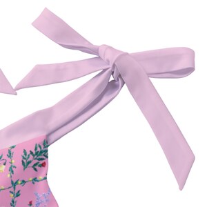 Peut inclure: Une bretelle de maillot de bain rose clair nou&eacute;e en n&oelig;ud, pr&eacute;sentant un motif r&eacute;p&eacute;titif de vignes vertes feuillues, de petites fleurs rouges et de minuscules fleurs jaunes sur un fond rose clair uni, avec une texture de tissu lisse et mate.