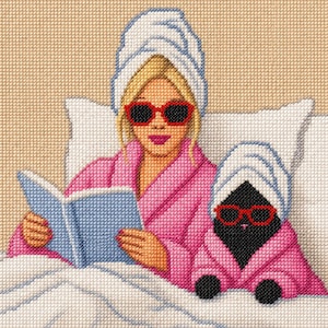 May include: Cross-stitch artwork of a woman and a small dog, both wearing red sunglasses and pink robes, with white towels on their heads. The woman is reading a blue book while lying in bed. The background is a light beige color.