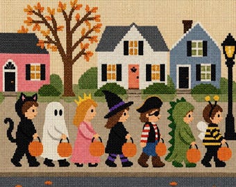 May include: A cross-stitch pattern depicting seven children in Halloween costumes walking in a line on a sidewalk in front of three houses. The costumes include a black cat, ghost, princess, witch, pirate, green dragon, and a bumblebee, each holding a pumpkin bucket.