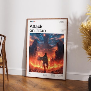 May include: A framed poster with the title "Attack on Titan". The artwork shows a silhouetted figure against a fiery landscape with dark, towering structures. The poster is displayed on a wooden floor, with a wooden chair visible.