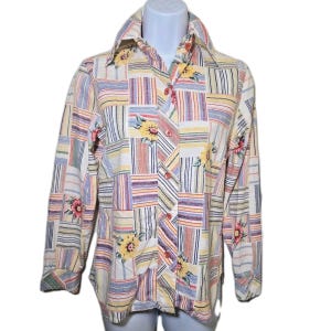 Op de afbeelding: Een button-down shirt met lange mouwen en een patchwork-ontwerp. Het shirt heeft een mix van gestreepte en bloemenpatronen in verschillende kleuren, waaronder geel, roze en blauw. Het shirt heeft een kraag en knoopsluitingen.