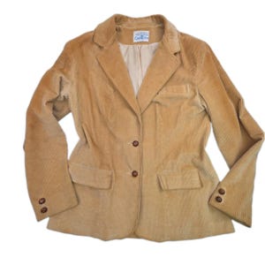 May include: A tan corduroy blazer featuring a notched lapel, two front buttons, two flap pockets, and two buttons on each sleeve cuff. The interior is lined with a light beige fabric and includes a label with the text CoaTree at the neckline.