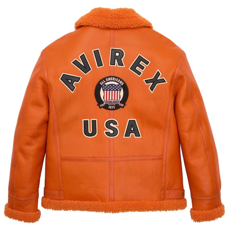 ack view of a handmade men's vibrant orange leather B3 bomber jacket featuring large black and white AVIREX USA varsity lettering and an American flag patch, with plush orange shearling fur trimming on the collar and hem.