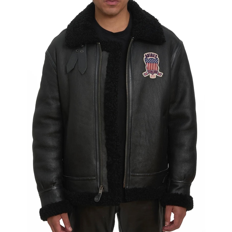 May include: Black leather jacket with a shearling collar and lining. The jacket features a zipper closure, a patch with an American flag design, and the word "AVIREX". The jacket has a classic aviator style.