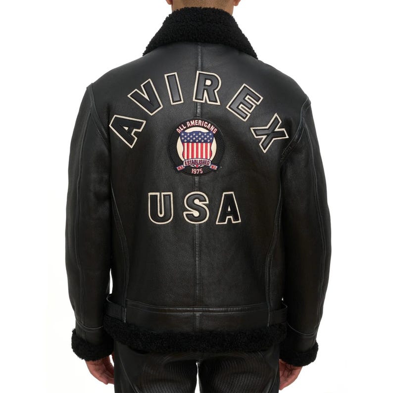 May include: Black leather jacket with a shearling collar and lining. The back features the word "AVIREX" in white lettering, along with a patch that says "ALL AMERICANS ESTABLISHED 1975 USA".