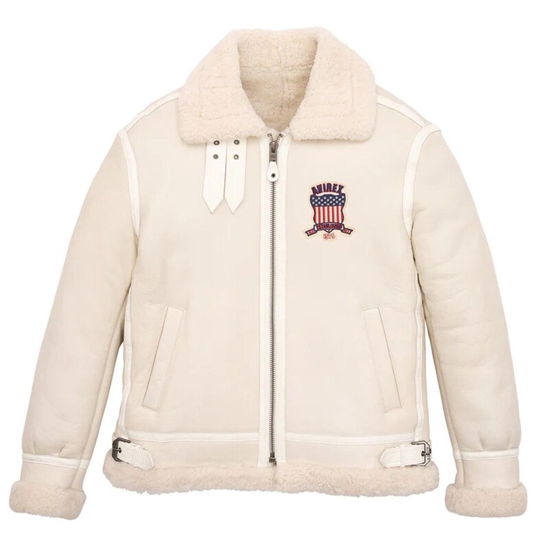 May include: Cream-colored aviator jacket with a shearling collar and lining. Features a full-length zipper, two front pockets, and a patch on the chest with the text "AVIREX". Includes buckle details on the waist and cuffs.