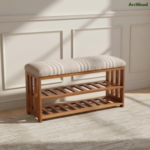 May include: Wooden shoe bench with two slatted shelves and a cushioned top. The bench has a light-colored fabric with vertical stripes and geometric patterns. The frame is made of brown wood.