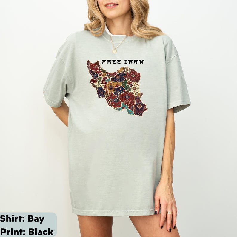 以下が含まれることがあります： 「FREE IRAN」の文字と、イランのカラフルな地図がプリントされた、薄い緑色のTシャツ。 地図のデザインには、赤、青、金など、さまざまな模様と色が使われています。 ゆったりとしたフィット感のシャツです。