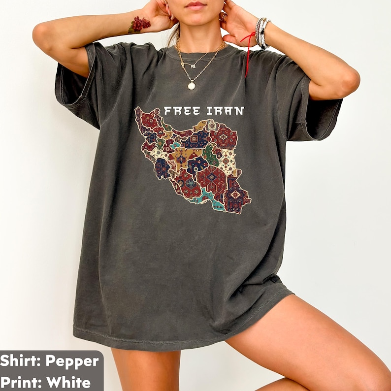 以下が含まれることがあります： 「FREE IRAN」の文字とイランのカラフルな地図がプリントされた、ペッパーカラーのTシャツ。 地図のデザインには、赤、青、金など、さまざまな模様と色が使われています。 このシャツは半袖で、ゆったりとしたフィット感です。