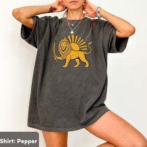 May include: Dark grey t-shirt with a golden lion holding a sword, set against a rising sun design. The shirt's color is pepper. The graphic is centered on the front of the shirt.