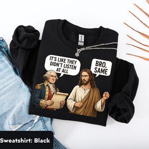 May include: Black sweatshirt featuring a graphic of George Washington and Jesus Christ in a humorous conversation. The text in speech bubbles reads "It's like they didn't listen at all" and "Bro, same."
