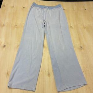 May include: Light blue wide-leg pants featuring a ribbed elastic waistband with a matching drawstring cord. The pants are constructed from a soft, solid-colored fabric and have a relaxed, straight-leg silhouette that extends to the hemline.