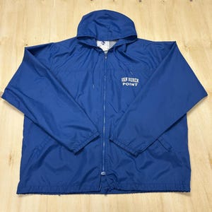 May include: A blue hooded jacket with a full-length zip and the text "VAN BUREN POINT" in white on the chest. The jacket features a drawstring hood and two front pockets. The jacket is made of a lightweight material.