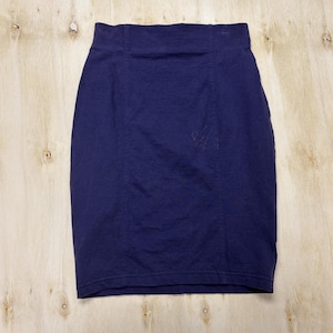 May include: A solid dark navy blue pencil skirt featuring a high-waisted design with a wide waistband and vertical seam detailing running down the front. The skirt is constructed from a smooth fabric and has a straight hemline at the bottom.