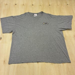 May include: A heather gray short-sleeve t-shirt with a crew neckline. The shirt features a small rectangular patch on the upper left chest with the text AIR in yellow and black lettering. A Nike brand tag is visible at the inside of the collar.
