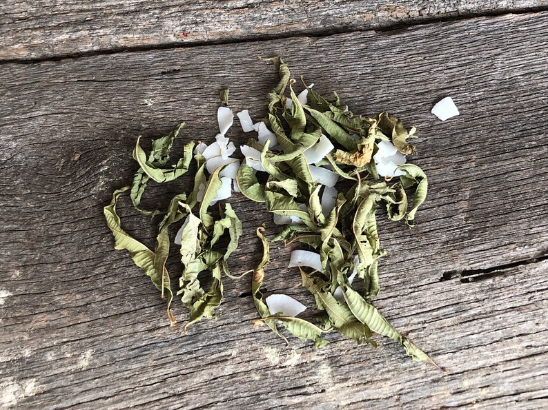 May include: Dried lemon verbena leaves and shredded coconut on a rustic wooden surface.