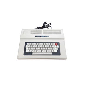 May include: A vintage Radio Shack TRS-80 Model III computer. The off-white computer has a full keyboard with white keys, a red enter key, and a dark grey border. The top has ventilation slits and a black power cord.