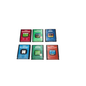 May include: A collection of six vintage Activision video game cartridges. The cartridges feature colorful labels with game titles like "Barnstorming," "Enduro," and "Ice Hockey." Each cartridge displays a small graphic of the game's gameplay.