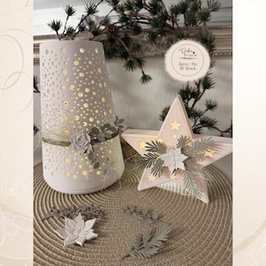 May include: A white cylindrical lantern with a perforated dot pattern and a star-shaped light, both decorated with green ribbons, white floral accents, and pine-like sprigs. A circular label displays the text Deko Friesin Datei für 3D Druck.