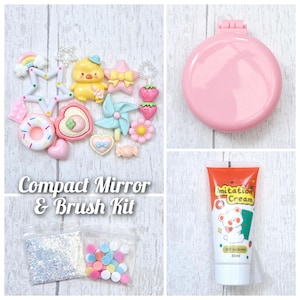 May include: A pink compact mirror and brush kit with decorative charms, including a yellow chick, stars, strawberries, and a donut. The kit also includes a tube of cream and bags of glitter and colourful beads. Text on the image reads "Compact Mirror & Brush Kit."