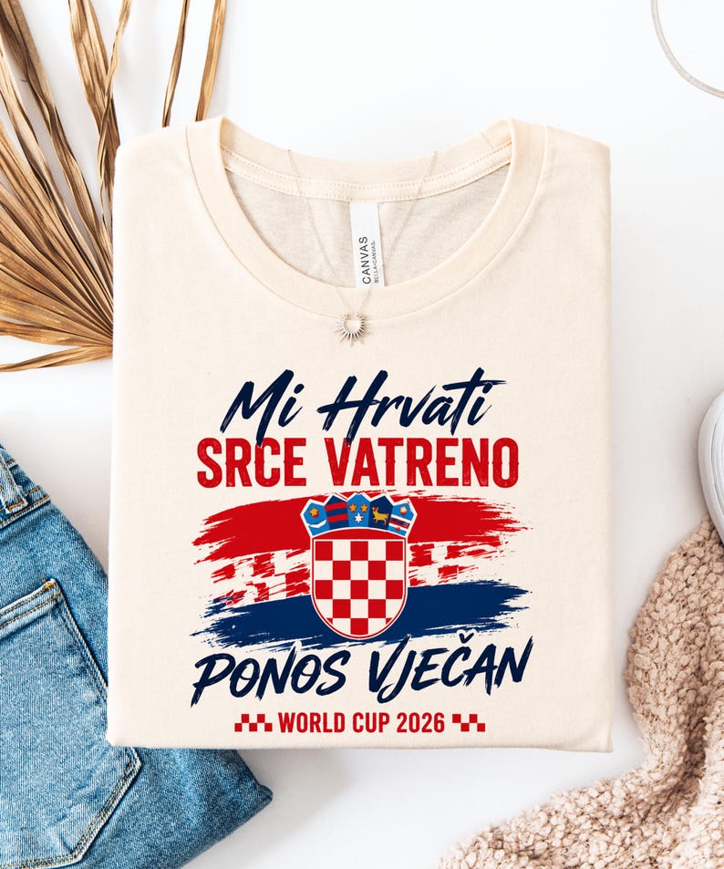 May include: Cream-colored t-shirt with the Croatian flag and text in blue and red. The shirt features the words "Mi Hrvati SRCE VATRENO PONOS VJEČAN WORLD CUP 2026" in a stylized font, celebrating Croatian pride.