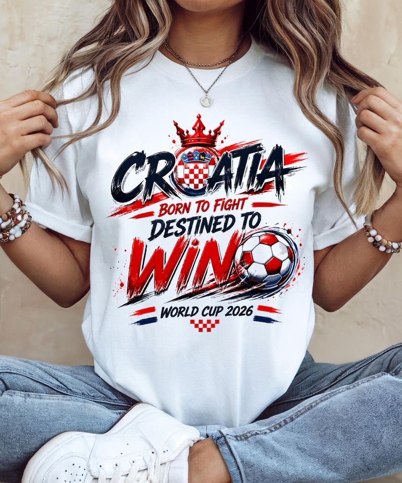 May include: White t-shirt with a Croatian soccer theme. The design features the word "CROATIA" in black and red, a crown, and a soccer ball. Text includes "BORN TO FIGHT, DESTINED TO WIN" and "WORLD CUP 2026".