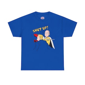May include: Royal blue t-shirt featuring a cartoon illustration. The graphic depicts a character punching another, with the words "SHUT UP!" in yellow. The shirt has a crew neck and short sleeves.
