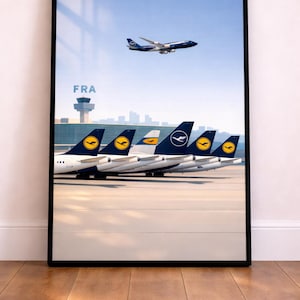 Puede incluir: Una impresión enmarcada que presenta varios aviones de Lufthansa estacionados en un aeropuerto, con un avión despegando en el cielo. La imagen incluye el texto "FRA" y una torre de control. Los aviones tienen un logotipo azul y amarillo.