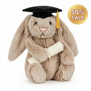 Puede incluir: Un conejo de peluche beige con orejas largas que lleva un birrete de graduación negro con una borla dorada. El conejo sostiene un diploma blanco enrollado atado con una cinta. Una insignia dorada circular muestra el texto 50% SALE.