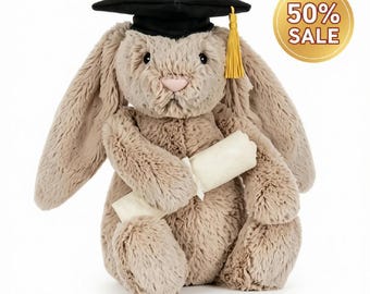 May include: A plush beige rabbit with long ears wearing a black graduation cap with a gold tassel. The rabbit is holding a rolled-up white diploma tied with a ribbon. A circular gold badge in the top right corner displays the text 50% SALE.