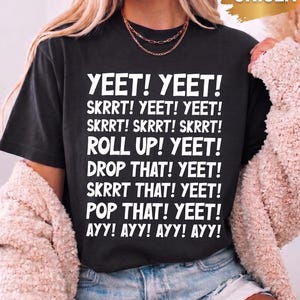 Könnte beinhalten: Ein schwarzes Kurzarm-T-Shirt mit weißem Text: YEET! YEET! SKRRT! YEET! YEET! SKRRT! SKRRT! SKRRT! ROLL UP! YEET! DROP THAT! YEET! SKRRT THAT! YEET! POP THAT! YEET! AYY! AYY! AYY! AYY! Das T-Shirt hat zudem ein goldenes UNISEX-Etikett.