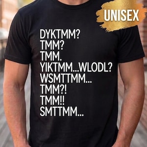 Puede incluir: Una camiseta negra de manga corta con texto blanco impreso en la parte delantera. El texto dice: DYKTMM? TMM? TMM. YIKTMM...WLODL? WSMTTMM... TMM?! TMM!! SMTTMM... Un gráfico dorado de pincelada con la palabra UNISEX se encuentra en la esquina superior derecha.