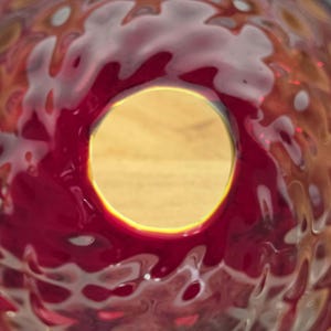View looking through the bottom interior opening of the red glass shade with yellow/UV case layer visible through the top glass opening