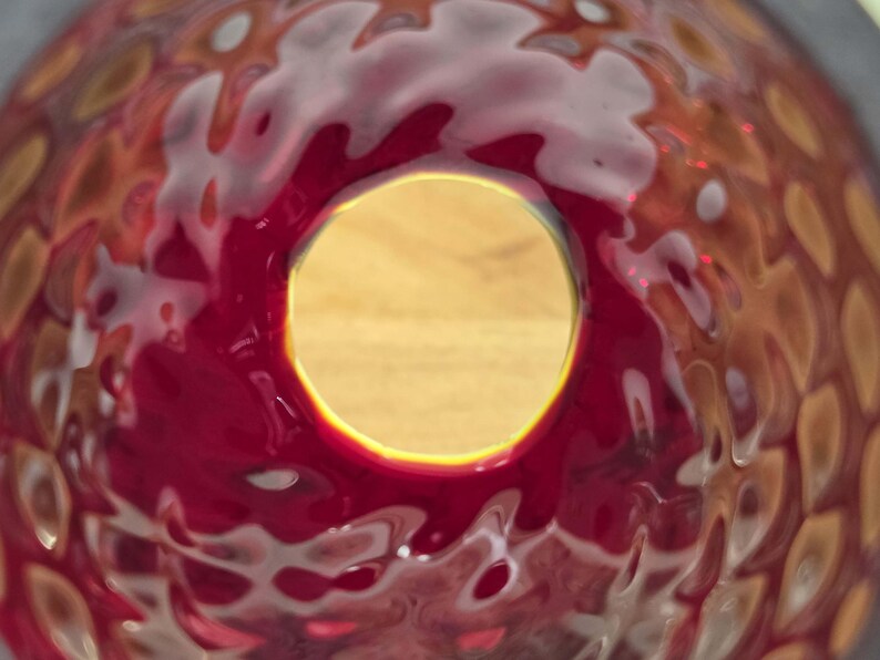 View looking through the bottom interior opening of the red glass shade with yellow/UV case layer visible through the top glass opening