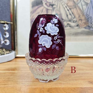 Fairy lamp labeled B with red glass shade, white painted flowers, and clear pressed glass base