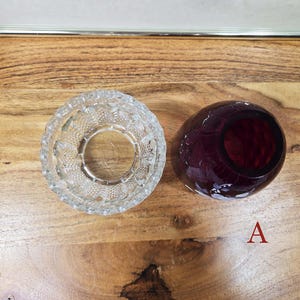 Top view of clear pressed glass base and red glass shade labeled A placed side by side on a wood surface