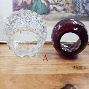 Bottom view of clear pressed glass base and opening of red glass shade labeled A placed side by side