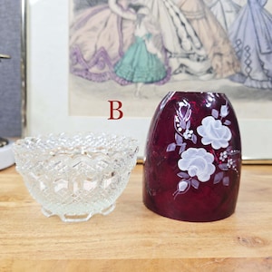 Clear pressed glass base beside red glass shade with white painted flowers labeled B