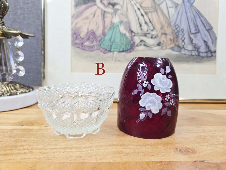 Clear pressed glass base beside red glass shade with white painted flowers labeled B