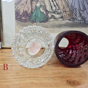 Bottom view of fairy lamp B showing clear glass base with paper label and red glass shade beside it