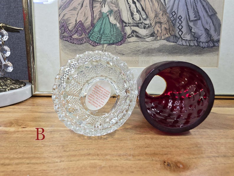 Bottom view of fairy lamp B showing clear glass base with paper label and red glass shade beside it