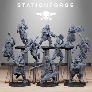 Könnte beinhalten: Eine Sammlung grauer Miniaturfiguren futuristischer Soldaten, jede mit Waffen und Ausrüstung. Die Figuren sind auf gestaffelten schwarzen Plattformen angeordnet. Der Text "STATIONFORGE" und ein Totenkopf-Logo befinden sich oben.