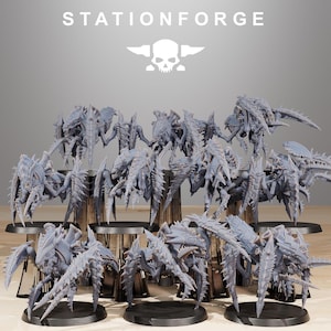 Op de afbeelding: Een verzameling grijze, insectachtige miniatuurfiguren met ingewikkelde details, gerangschikt op zwarte bases. De figuren hebben meerdere poten en stekelige uitsteeksels. De tekst "STATIONFORGE" staat boven de figuren, samen met een schedellogo.