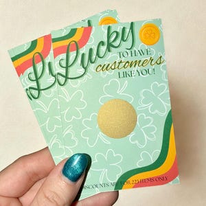 Könnte beinhalten: Stapel von Karten zum Thema St. Patrick's Day mit mintgrünem Hintergrund und weißem Kleeblattmuster. Die Karten haben das Wort "Lucky" in grüner Schrift, goldfarbenen Text "to have customers like you!" und einen goldenen Rubbelkreis.