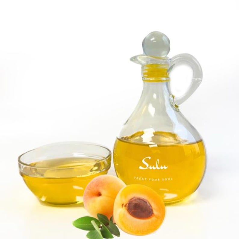 May include: A clear glass bottle and bowl filled with yellow liquid, next to fresh apricots. The bottle has a handle and a stopper. The text "Sulu TREAT YOUR SOUL" is printed on the bottle.