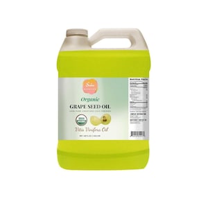 Puede incluir: Un gran bidón de plástico amarillo verdoso de aceite de semilla de uva orgánico. La etiqueta incluye el texto "Organic Grape Seed Oil" y "100% Pure Unrefined Cold Pressed". El bidón tiene un asa y una tapa blancas. El volumen neto es de 3,79 litros.