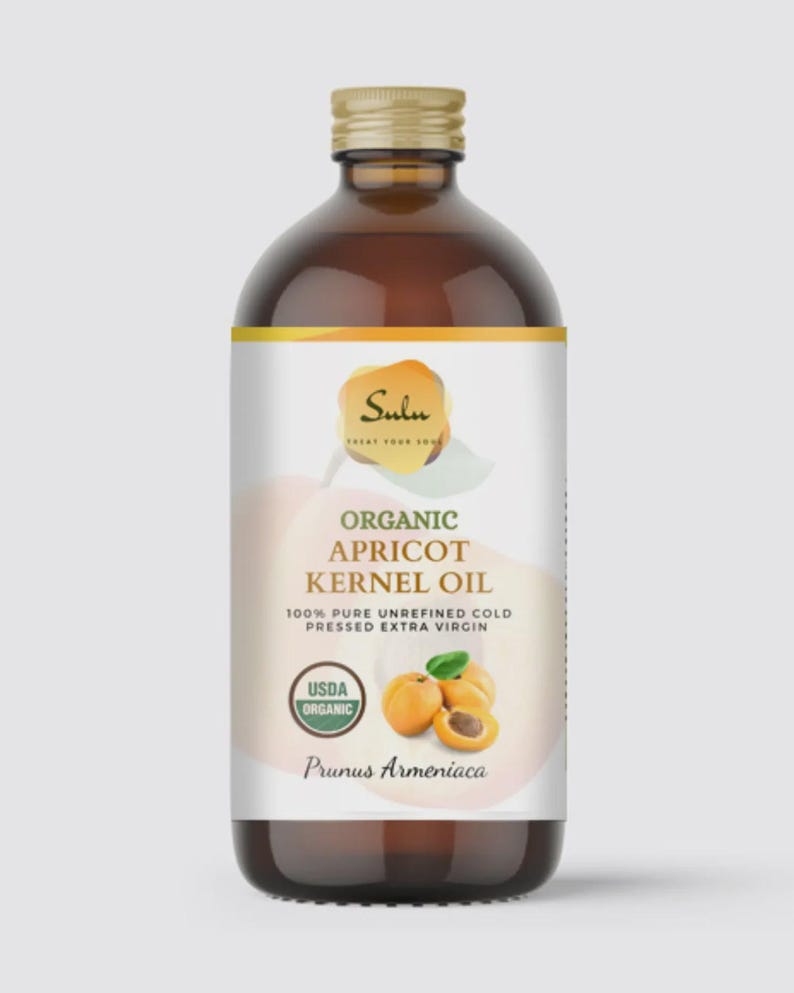 May include: A brown glass bottle of Sulu Organic Apricot Kernel Oil. The label features the text "Organic Apricot Kernel Oil" and "100% Pure Unrefined Cold Pressed Extra Virgin". The label also includes a USDA Organic seal and an illustration of apricots.