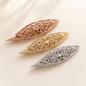 May include: Three elongated, pointed hair clips in rose gold, yellow gold, and silver tones. Each clip features a delicate, openwork filigree pattern composed of interconnected circular motifs, creating a detailed, lace-like metal structure.