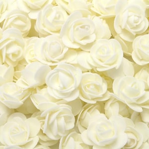 May include: A dense collection of numerous small, cream-coloured artificial roses. Each flower features multiple layered petals arranged in a circular, blooming pattern, creating a uniform and textured surface of soft, off-white floral shapes.